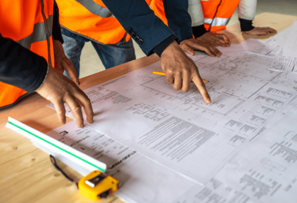 Construction workers point to a blueprint