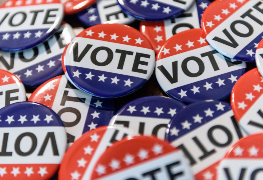 A pile of red, white, and blue pins with "Vote" written on them.